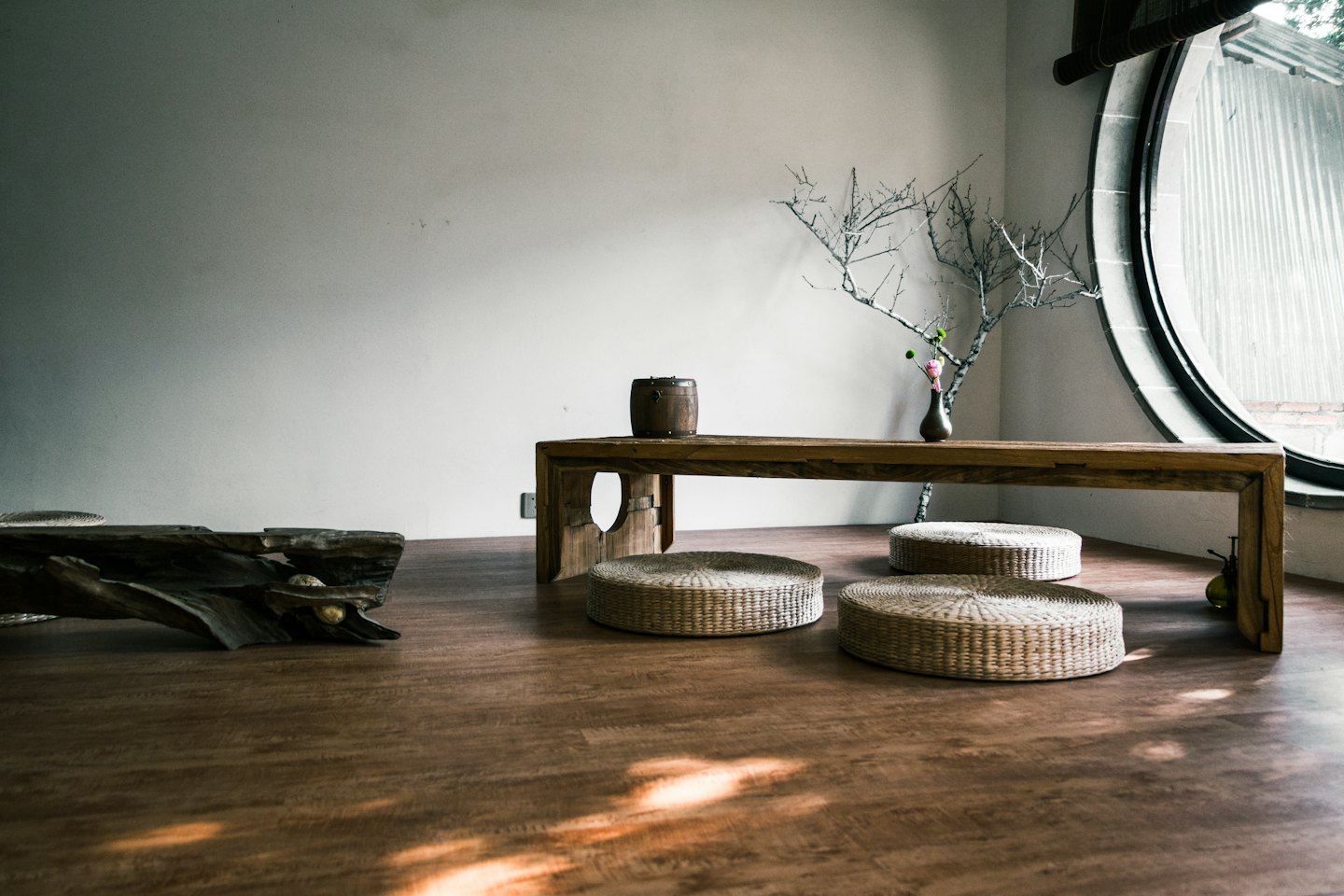 Minimalistischer Raum mit niedrigem Holztisch und Bodenkissen.