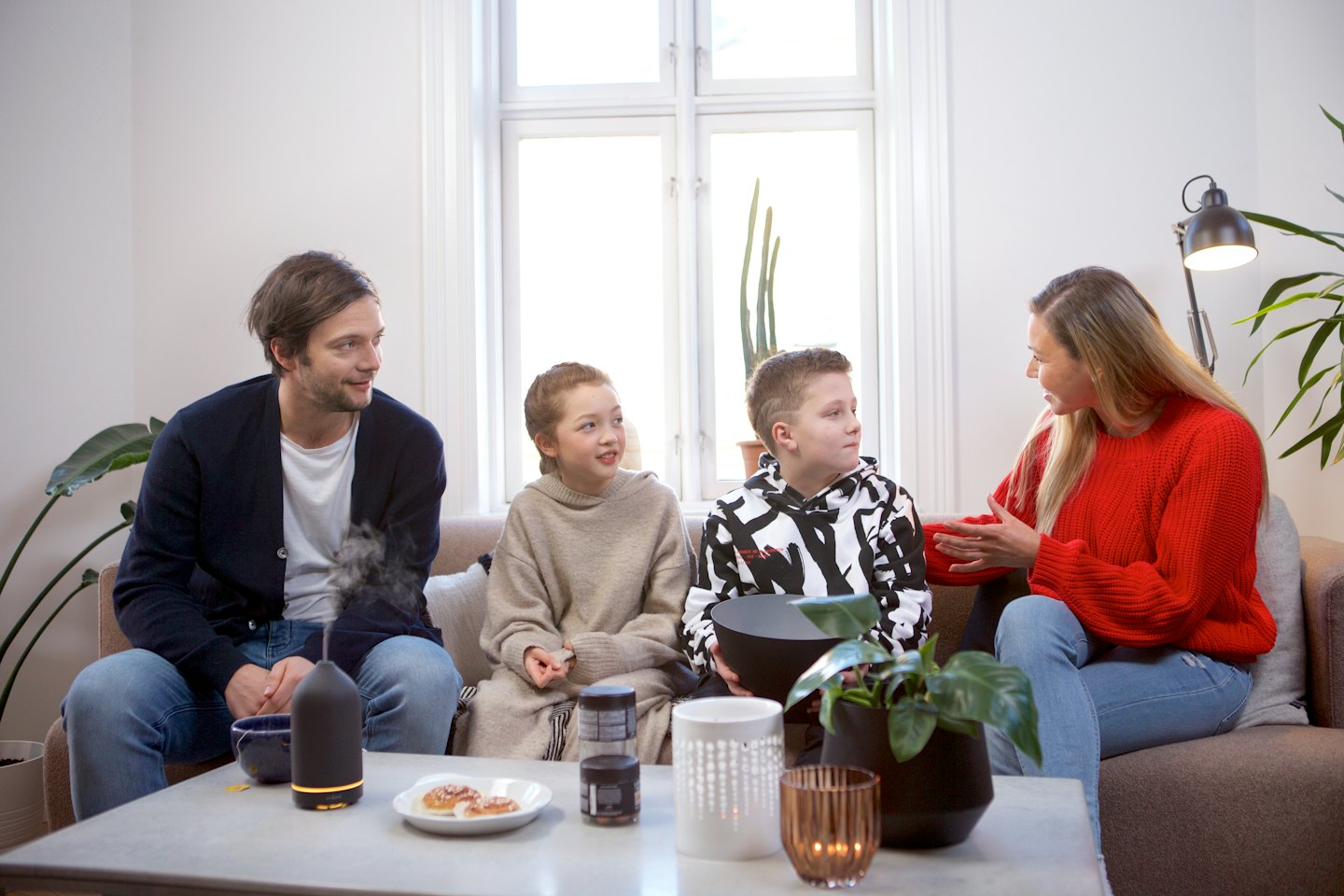 Eine Familie unterhält sich auf einem Sofa im Wohnzimmer.